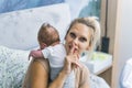 Quiet time. Blond caucasian woman shushing the camera while holding her little fragile infant baby boy on her arms Royalty Free Stock Photo