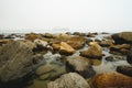 Quiet water, seashore rocks, and silhouette of vessel on a horizon at an overcast day, Morro Bay, CA Royalty Free Stock Photo