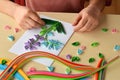 Quilling technique. Girl making decorations or greeting card. Paper strips, flower, scissors. Handmade crafts on holiday: Birthday Royalty Free Stock Photo