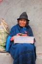 Quilotoa, Ecuador, 2-3-2020: An Andean lady dressed in the local style with an andean hat peeling potatoes