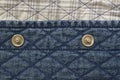 Quilted fabric denim cloth element texture close up with metal buttons