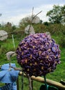 quilted purple ball flower on a green stem inside the brass double bed of flowers.. FLOWER BED