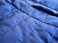 Quilted sports jacket fabric sample. Blue polyester material soaked in rain and wind. Smooth, high-quality, accurate seams