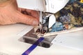 Quilter sewing on binding to quilt.