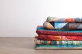 Quilts stacked on wooden table on white wall background