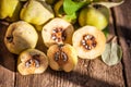 Quince fruits on a wooden background. Harvest of autumn fruits. Yellow tart hard fruit. Cut apple-quince with leaf