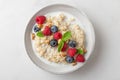 Quinoa porridge with fresh berries, nuts and mint in a bowl on white background. top view. healthy breakfast Royalty Free Stock Photo