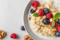 Quinoa porridge with fresh blueberry, raspberry, walnuts, honey and mint in a bowl on white background. top view Royalty Free Stock Photo