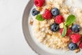 Quinoa porridge with fresh blueberry, raspberry, walnuts, honey and mint in a bowl on white background. top view Royalty Free Stock Photo