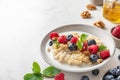 Quinoa porridge with fresh blueberry, raspberry, walnuts and mint in a bowl on white background. close up Royalty Free Stock Photo