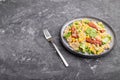 Quinoa porridge with green pea, corn and dried tomatoes on ceramic plate on a gray concrete background. Side view, copy space