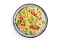 Quinoa porridge with green pea, corn and dried tomatoes on ceramic plate isolated on white background. Top view