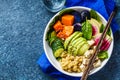 Quinoa salad with tofu, avocado and vegetables in white bowl, top view, blue background. Vegan breakfast Royalty Free Stock Photo