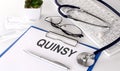 QUINSY text on white paper on white background. stethoscope ,glasses and keyboard