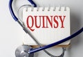 QUINSY word on notebook with medical equipment on background