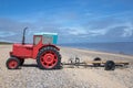 Quirky little red vintage diesel tractor with boat trailer