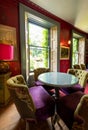 Eclectic living room with brightly coloured velvet upholstered chairs, pink lampshade and wooden floor.