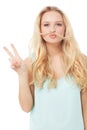 Give peace a chance. A quirky young blonde showing you a peace sign with her hair over her mouth - isolated.