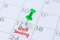 Quit Smoking written on a calendar with a green push pin to rem