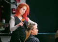 QUITO, ECUADOR - OCTOBER, 25, 2017: Close up of a hair stylist drying blond woman using a hair dryer and round brush in