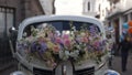 Arrangement of red and yellow roses on the hood of an old white car parked on a street