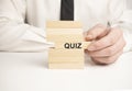 quiz on wooden dices in male hand on black background