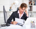 Quizzical man working on his laptop in white room Royalty Free Stock Photo