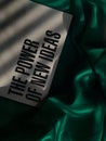 Quote "the power of new ideas" on a green cloth, with sunlight