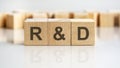 R AND D - letters on wooden cubes. business as usual concept image. front view