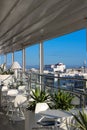 The hotel`s open verandah has empty white tables, chairs and a transparent wall