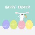 Rabbit with carrot sitting on painting egg shell set. Painted eggs with thread and bow. Happy Easter bunny. Farm animal. Cute cart Royalty Free Stock Photo