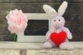 Rabbit doll holding red heart shape near blank frame