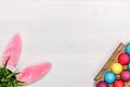 Rabbit ears, a flower pot with artificial green grass, colorful eggs in a cardboard box. Easter concept. Copy space Royalty Free Stock Photo