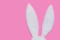 Rabbit ears made of white fur on pink pastel background. The concept of Easter