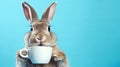 rabbit holding a mug with hot coffee on a blue background with copy space Royalty Free Stock Photo