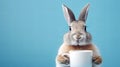 rabbit holding a mug with hot coffee on a blue background with copy space Royalty Free Stock Photo