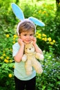 Rabbit kid with bunny ears. Hare toy. Happy easter. Childhood. Little boy child in green forest. Egg hunt on spring Royalty Free Stock Photo