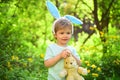 Rabbit kid with bunny ears. Hare toy. Little boy child in green forest. Egg hunt on spring holiday. love easter. Family Royalty Free Stock Photo