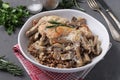 Rabbit meat with buckwheat, mushrooms and sour cream sauce in a light plate on a dark background