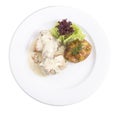 Rabbit in white sause with baked potato in white plate.