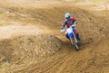 The racer on a motorcycle participates in race motocrosses, goes on sand. Red blue suit.