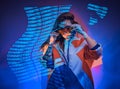 Racer woman posing in studio in neon, looking stylish and holding sunglasses