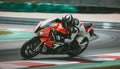 Racing motorbike rider in helmet and gear racing at high speed on race track with motion blur