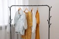 Rack with bag and stylish women\'s clothes on hangers near light wall indoors Royalty Free Stock Photo