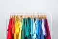 Rack with bright clothes on blue background. Rainbow colors Royalty Free Stock Photo