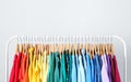 Rack with bright clothes on light blue. Rainbow colors Royalty Free Stock Photo