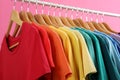 Rack with bright clothes on pink background Royalty Free Stock Photo