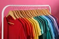 Rack with bright clothes on pink. Rainbow colors Royalty Free Stock Photo