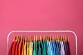 Rack with bright clothes on pink background. Rainbow colors Royalty Free Stock Photo