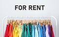 Rack with bright clothes for rent on light background Royalty Free Stock Photo